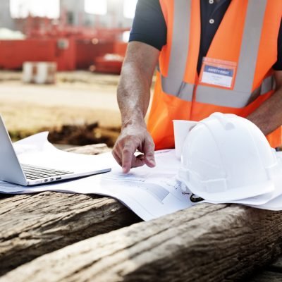 Closeup of contractor in construction site pointing at plan on wooden sleeper